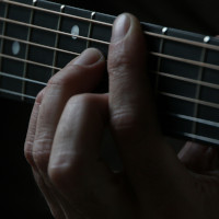 Mano che compone accordo su manico di chitarra